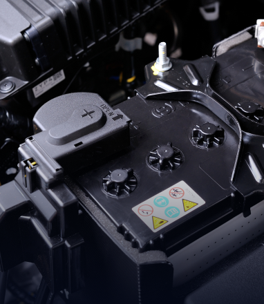 Black battery compartment with warning label and terminals in a machine interior