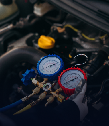 Mechanic using blue and red gauges to check car air conditioning under the hood