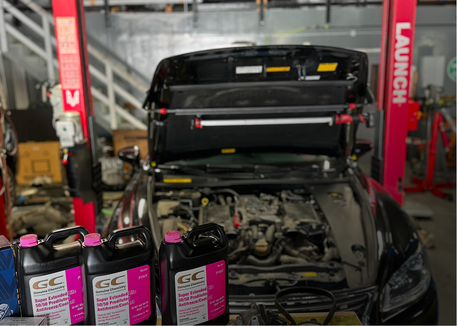 Mechanic working on a car engine in a garage, with orange gloves and engine bay exposed