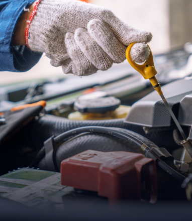 Gloved hand using a dipstick to check car engine oil in the engine bay