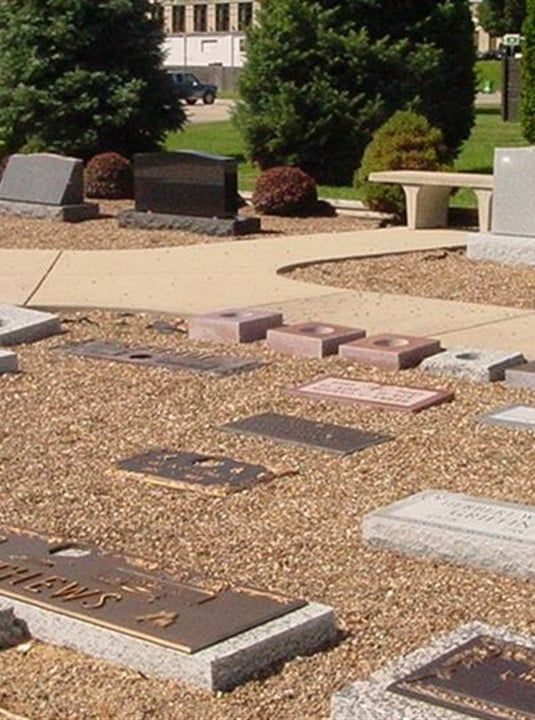 Outdoor memorial with engraved stone plaques and benches in a landscaped garden.