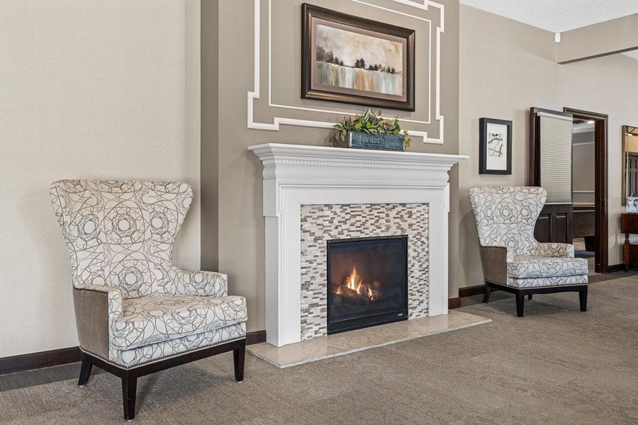 Elegant living room with two patterned armchairs flanking a white fireplace and framed wall art.