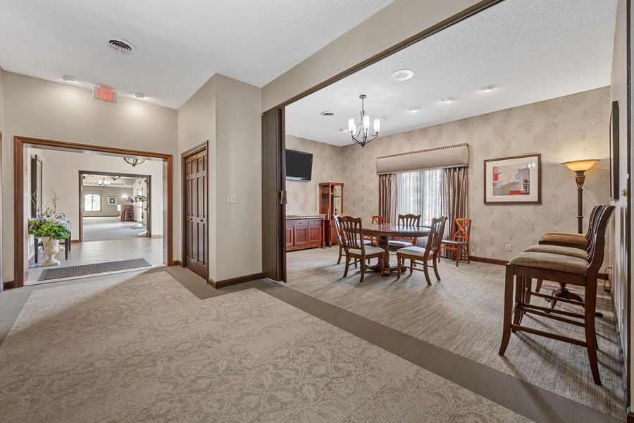 Spacious beige living and dining room with carpet, wood furniture, and a chandelier