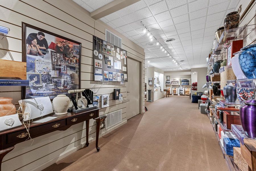 Hallway of a thrift store with display tables, shelves of donated goods, and framed wall art.