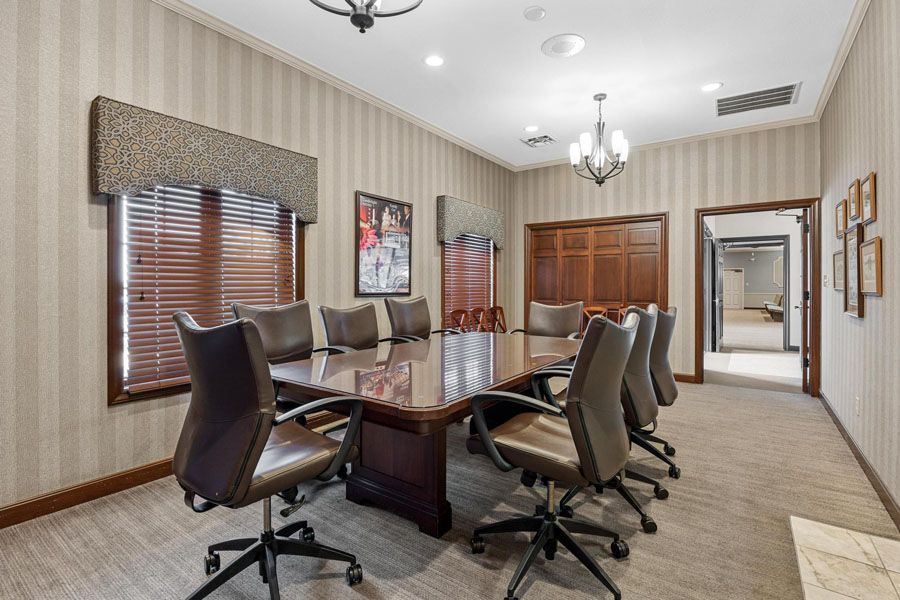 Elegant conference room with glass table, black chairs, wood cabinetry, and striped wallpaper