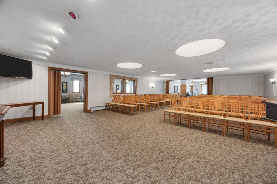 Spacious church hall with rows of wooden pews, carpeted floor, and large round ceiling lights