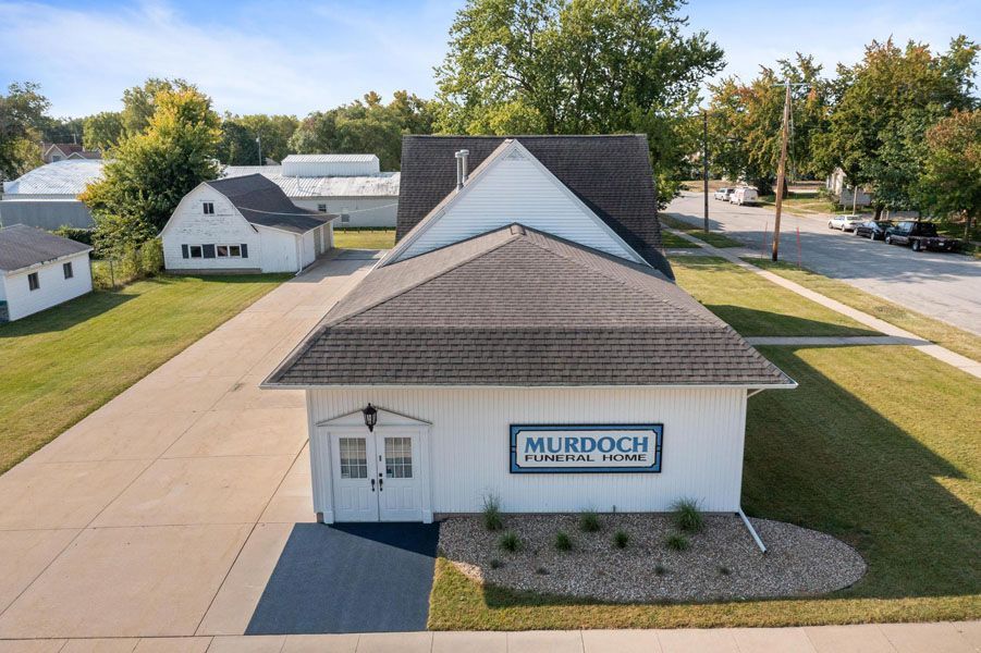 White Murdoch building with gray roof beside a paved road on a sunny day