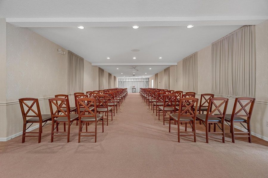 Empty conference room with rows of wooden chairs and a central aisle under recessed ceiling lights