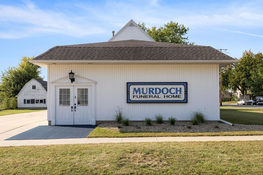 White Murdoch building with blue sign, single door, and garage on a sunny day