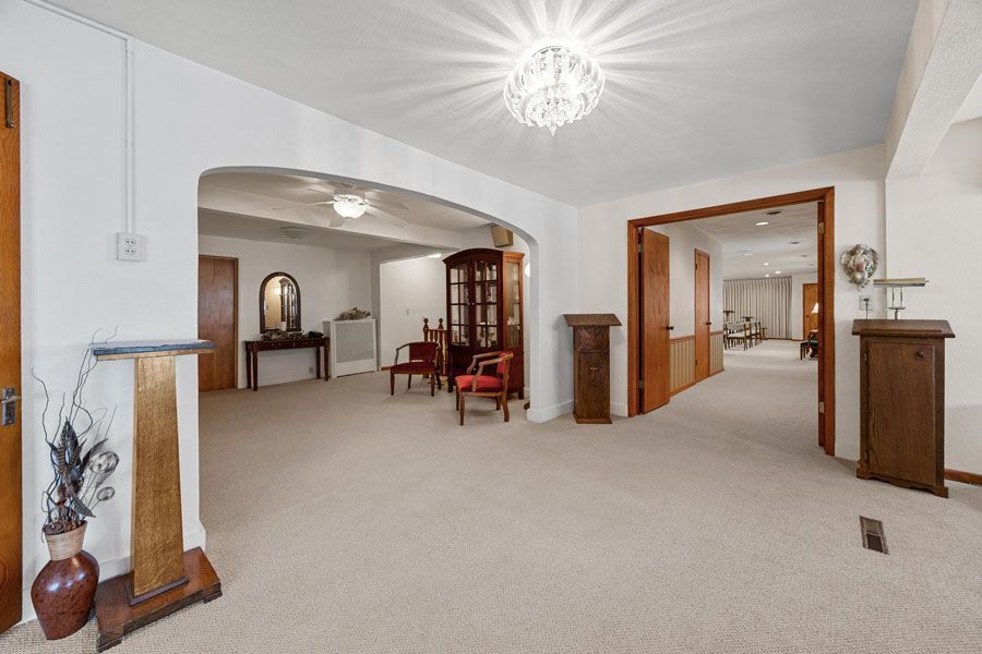 Spacious beige living room with arched openings, hardwood accents, and a chandelier