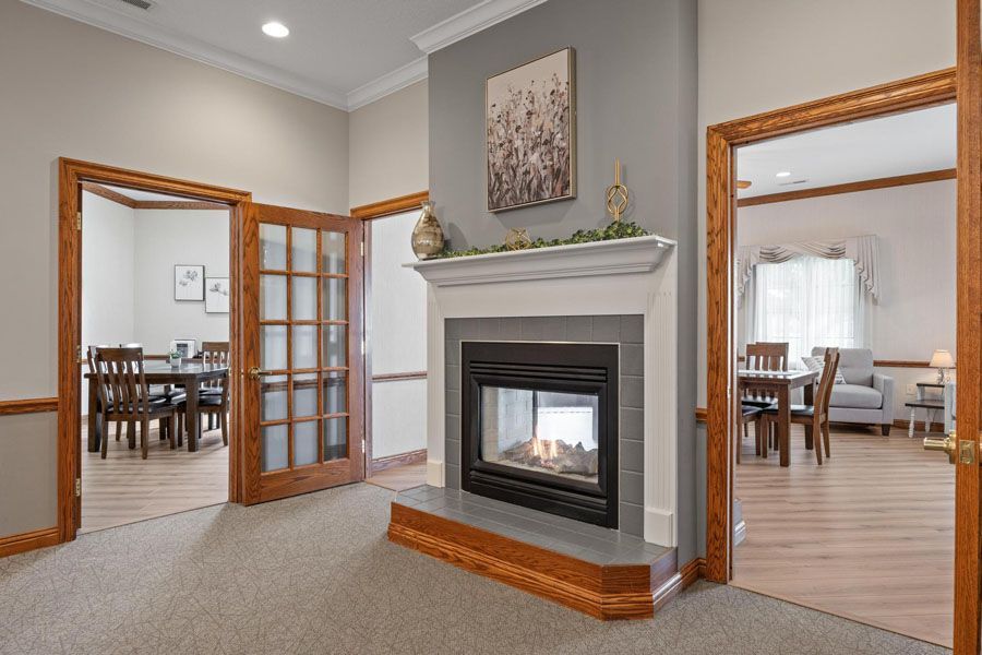 Bright living room with a fireplace, French doors, and views into a dining area and another room