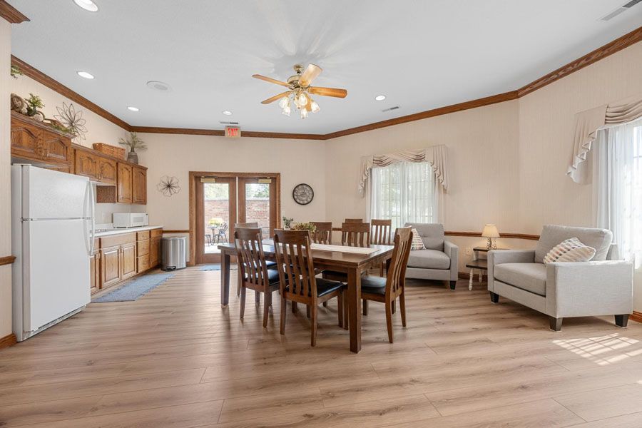 Spacious open-plan kitchen and dining room with wooden table, white cabinets, and light wood flooring