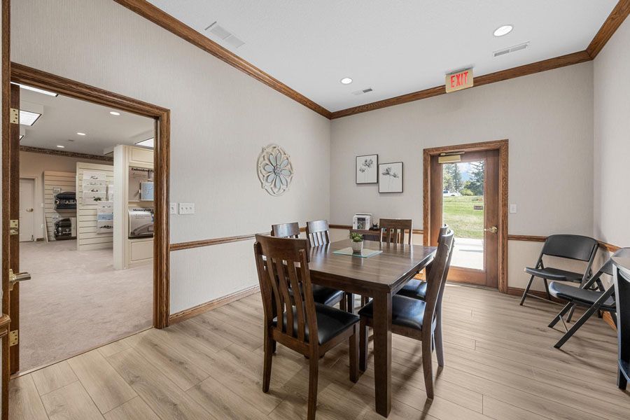 Dining room with wooden table and chairs, light wood floors, and a door opening to a sunny patio.