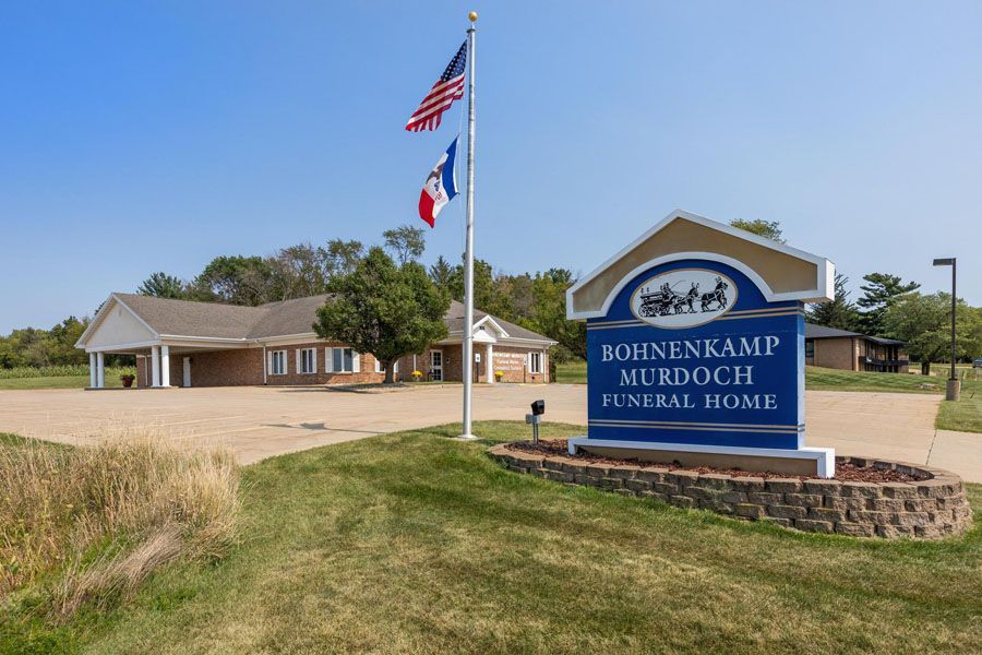 Boinenkamp Funeral Home sign with flags and building on a grassy roadside lot