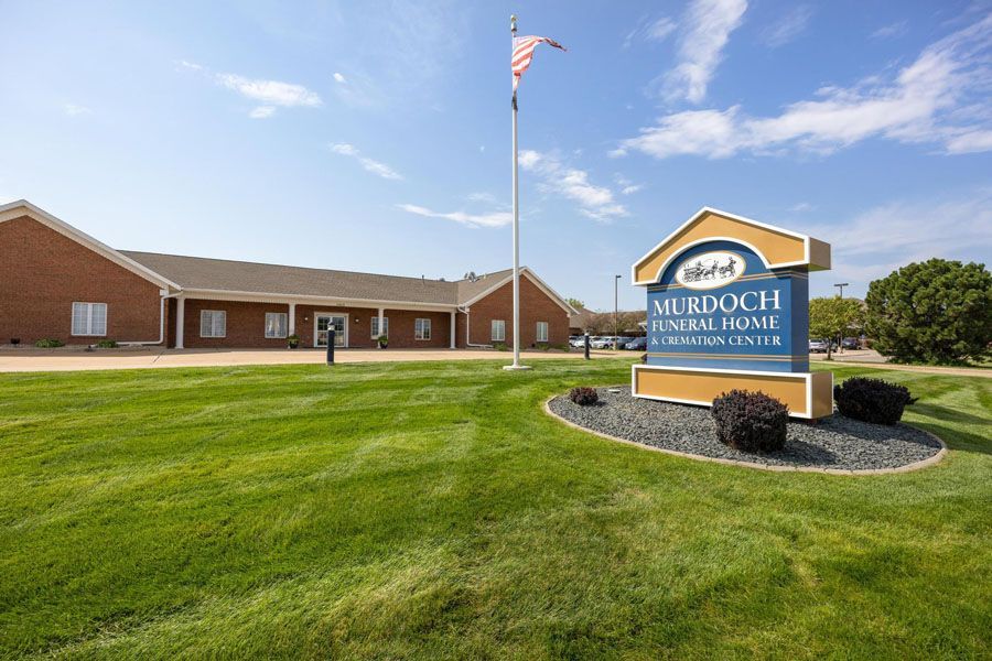 Vurdoch School Center sign in front of a brick building and flagpole on a sunny lawn