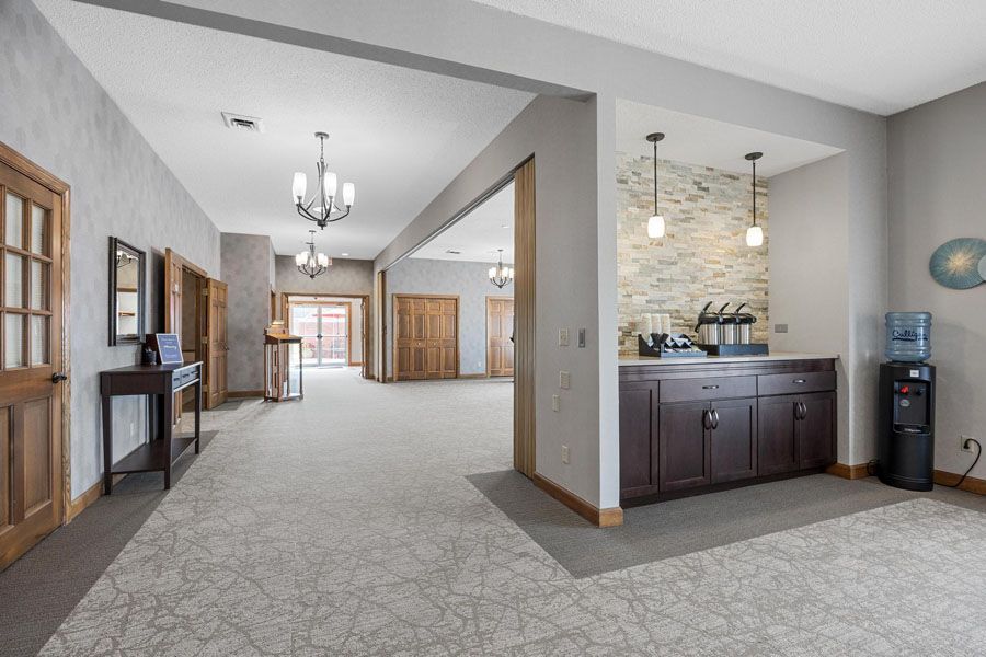 Open-concept living area with carpet, chandeliers, fireplace, and kitchen counter with pendant lights.