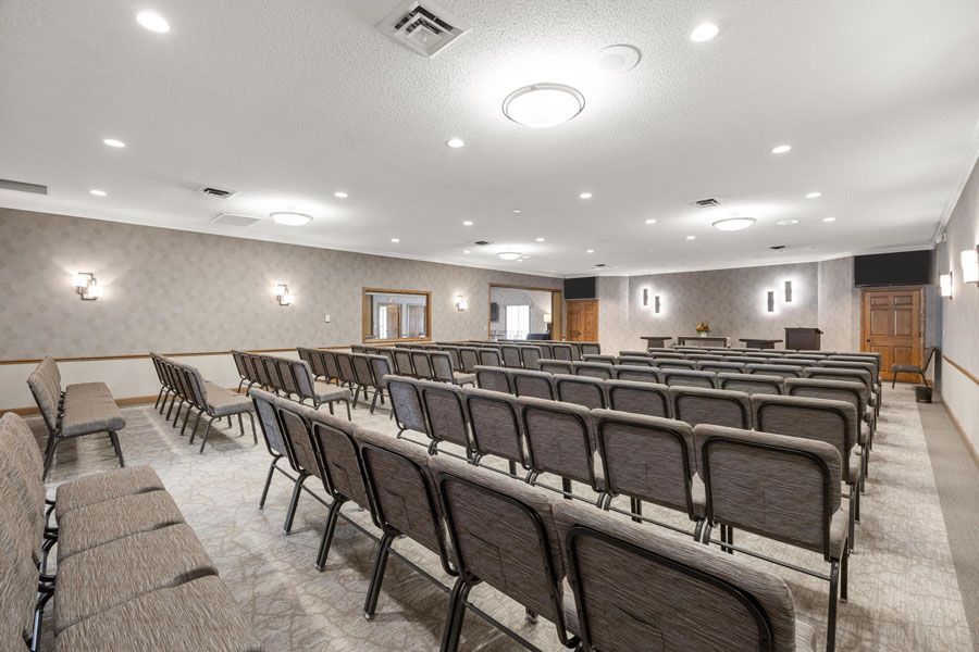Empty conference room with rows of brown chairs, carpeted floor, and recessed ceiling lights
