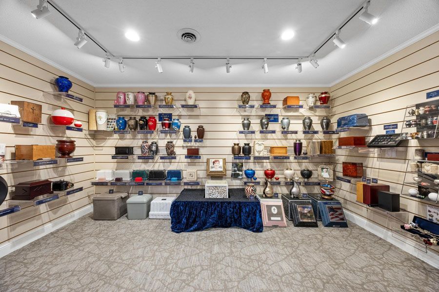 Cluttered shop display with shelves of handbags, backpacks, and small cases around a central table