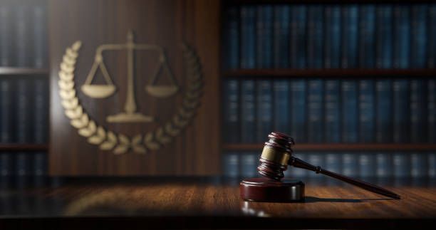Judge’s gavel on a wooden desk in a legal library with scales of justice in the background