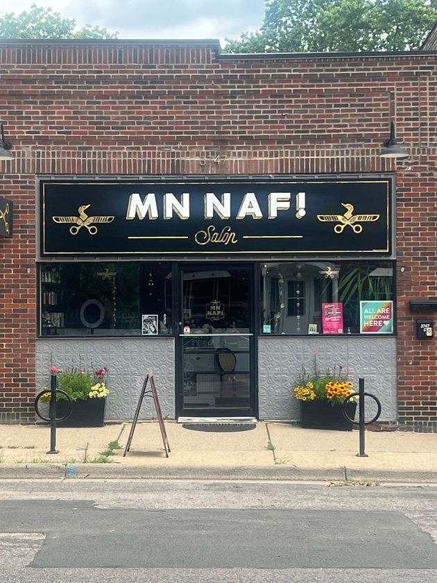 MN NAF! salon storefront with brick facade, black sign, glass door, and flower boxes.