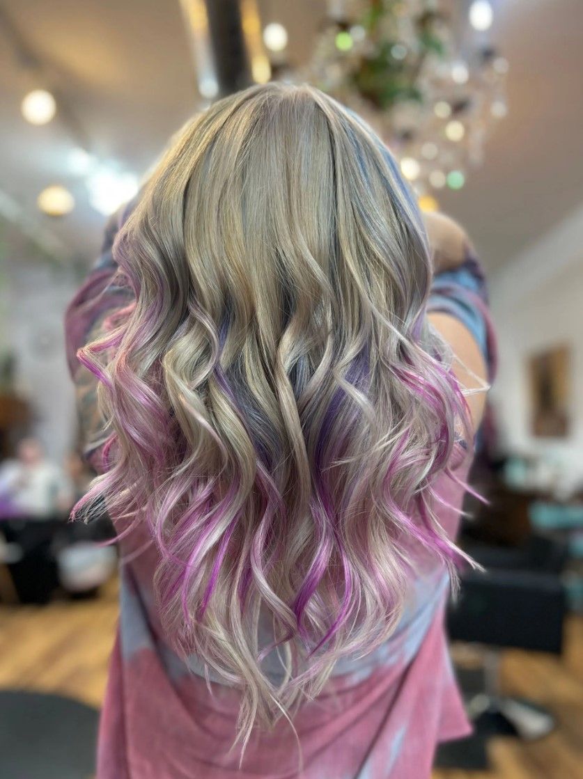 Woman with wavy, ash blonde hair and pink and purple tips.
