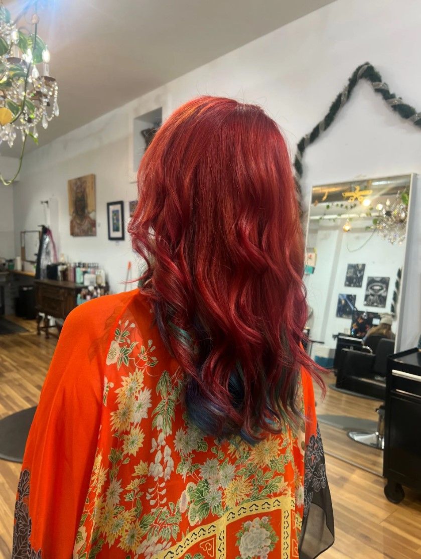 Person with red hair and orange kimono in a salon, near a mirror.