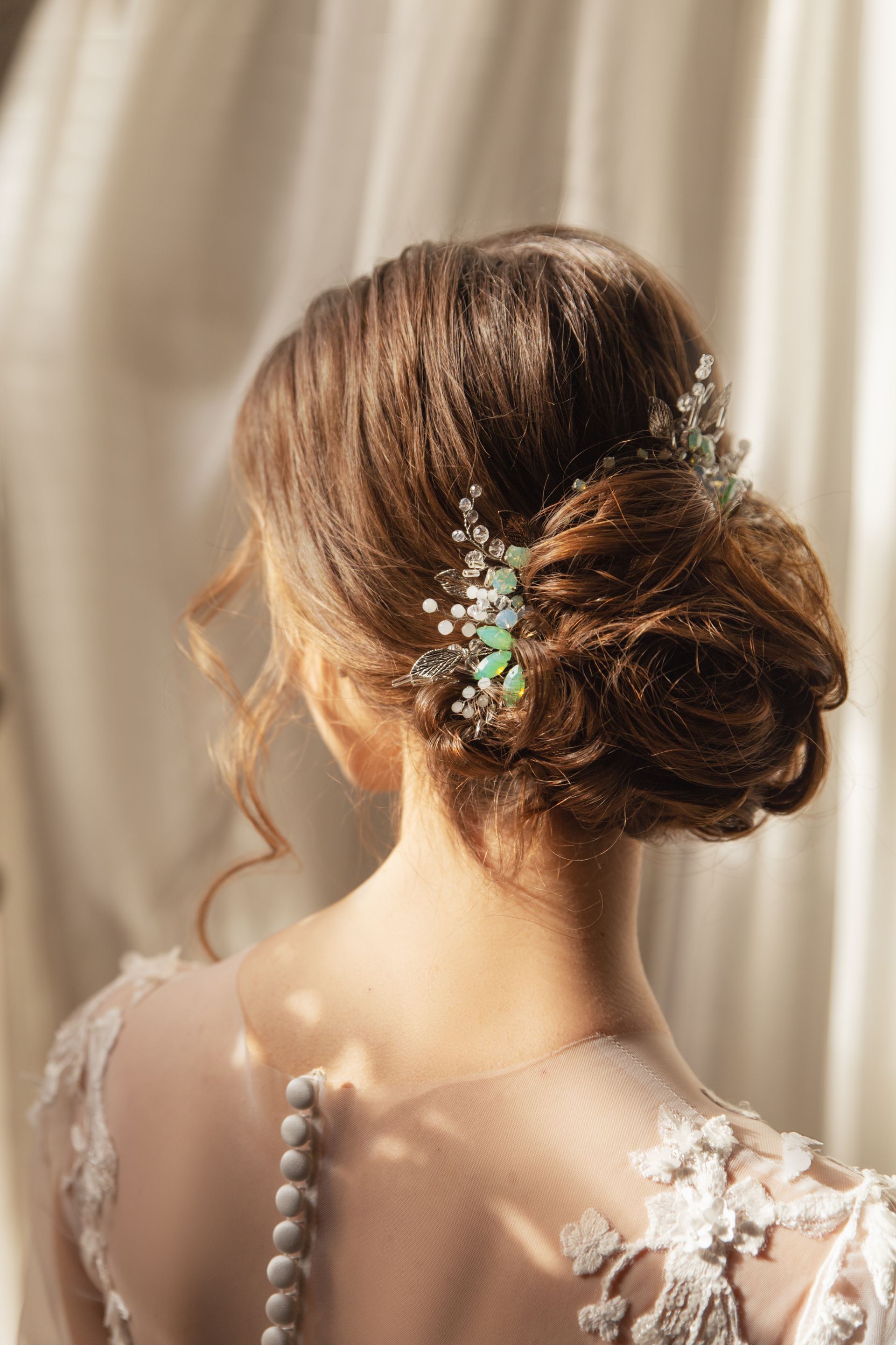 Woman's updo hairstyle with a decorative hairpiece. Beige dress with lace details.