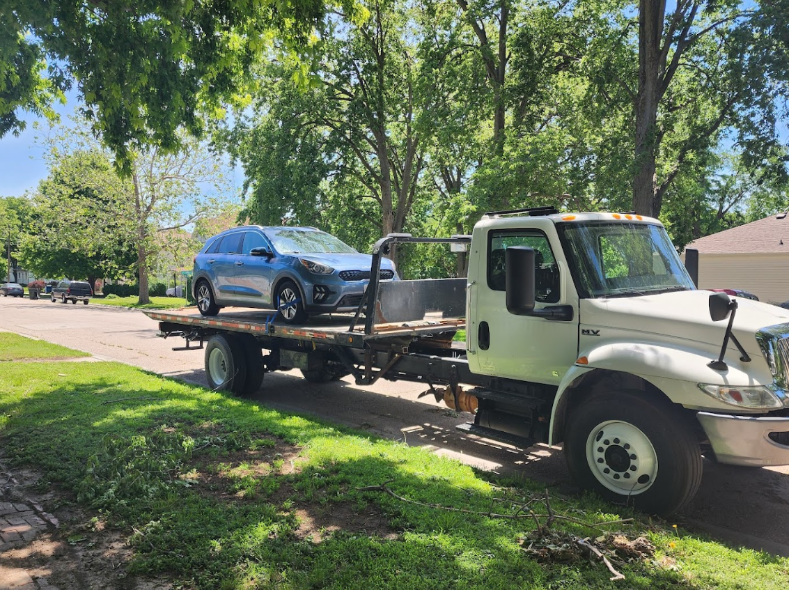 A tow truck is towing a car on the back of it.