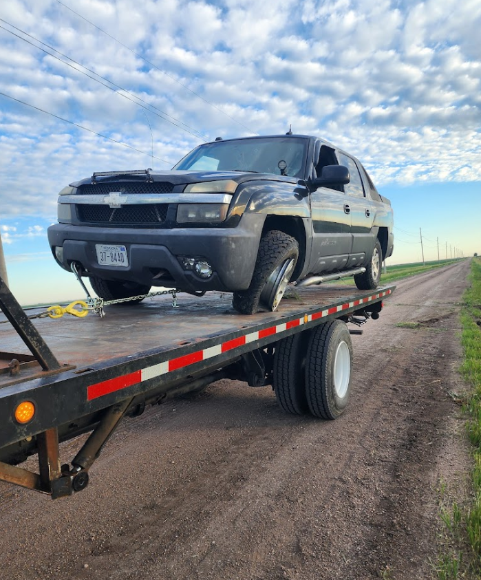 A black suv is sitting on top of a flatbed tow truck.