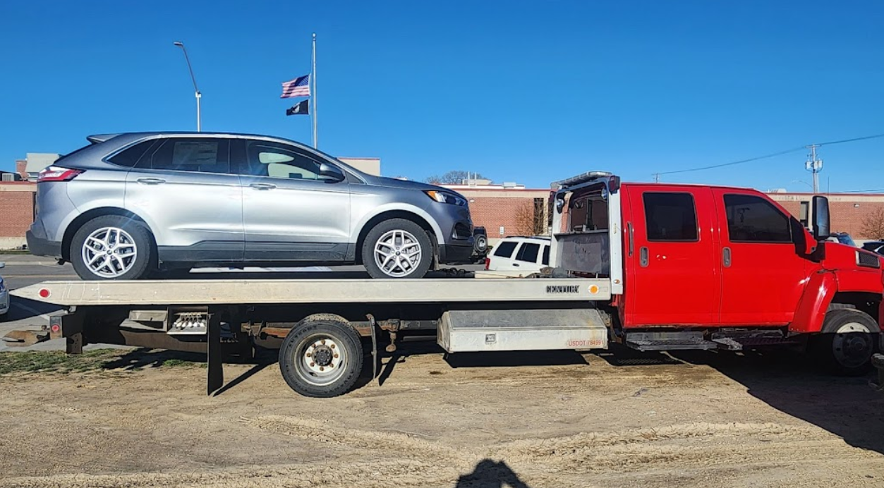 A red tow truck is towing a silver suv.