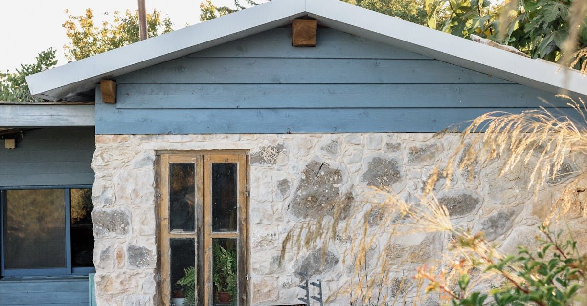 Stone cottage exterior with blue siding, wooden door, and natural landscaping.
