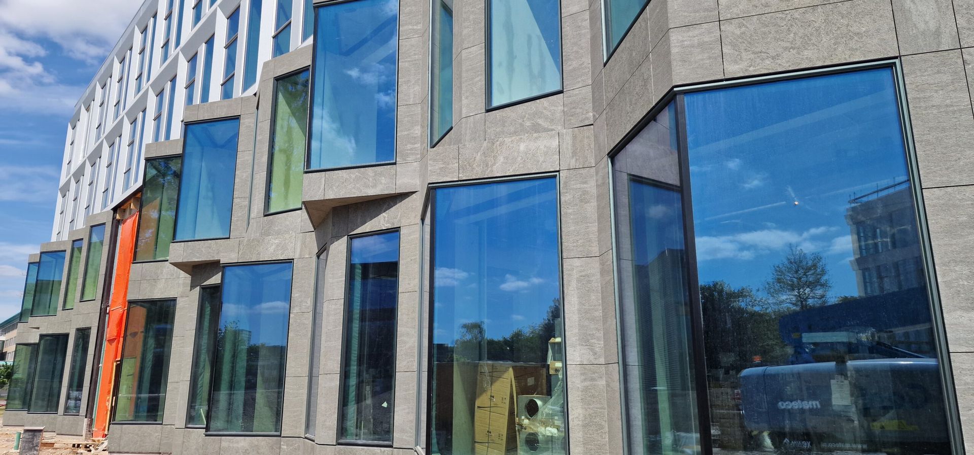 Er wordt een groot gebouw met veel ramen gebouwd.