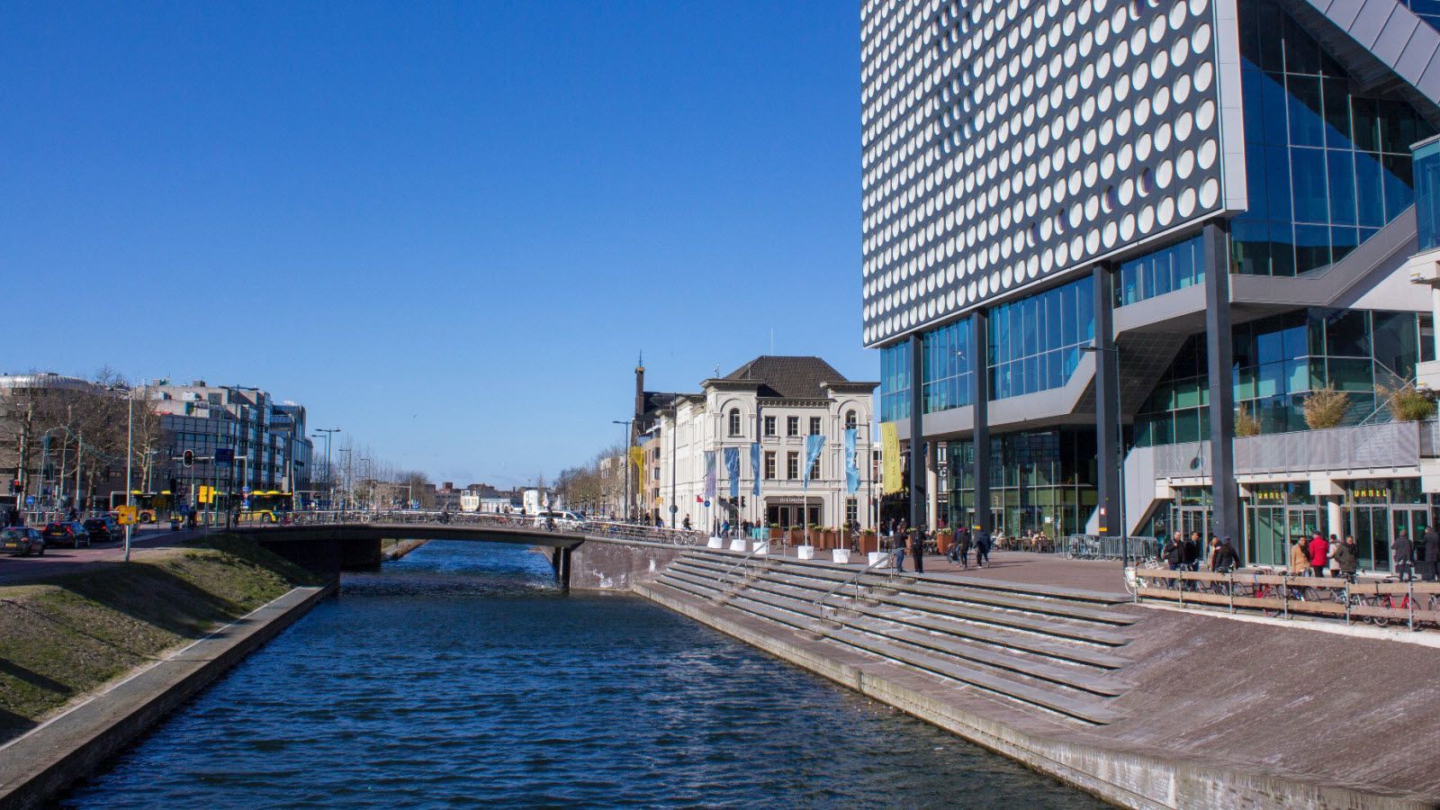 Een groot gebouw staat naast een rivier in een stad.