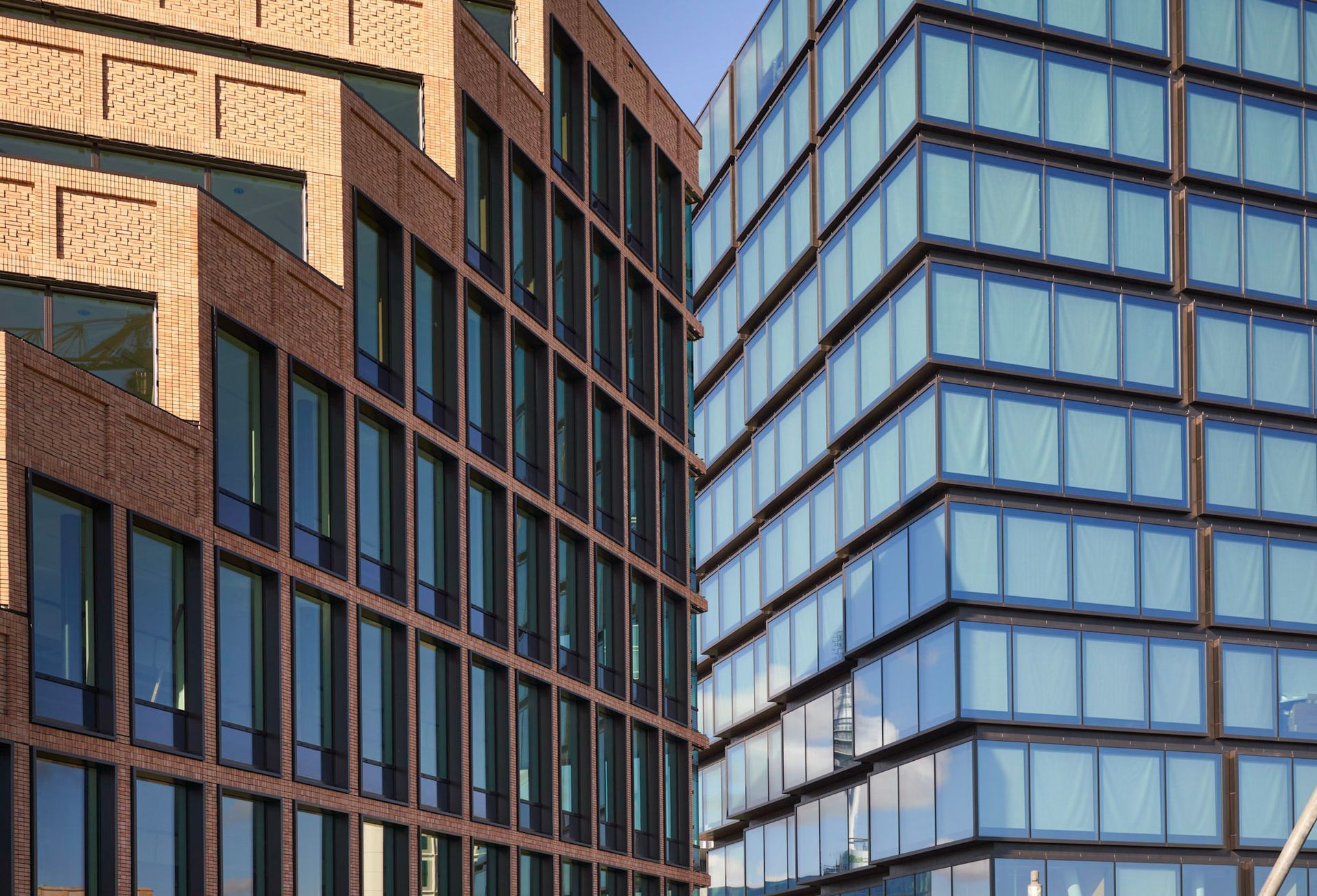 Een bakstenen gebouw en een glazen gebouw staan naast elkaar.