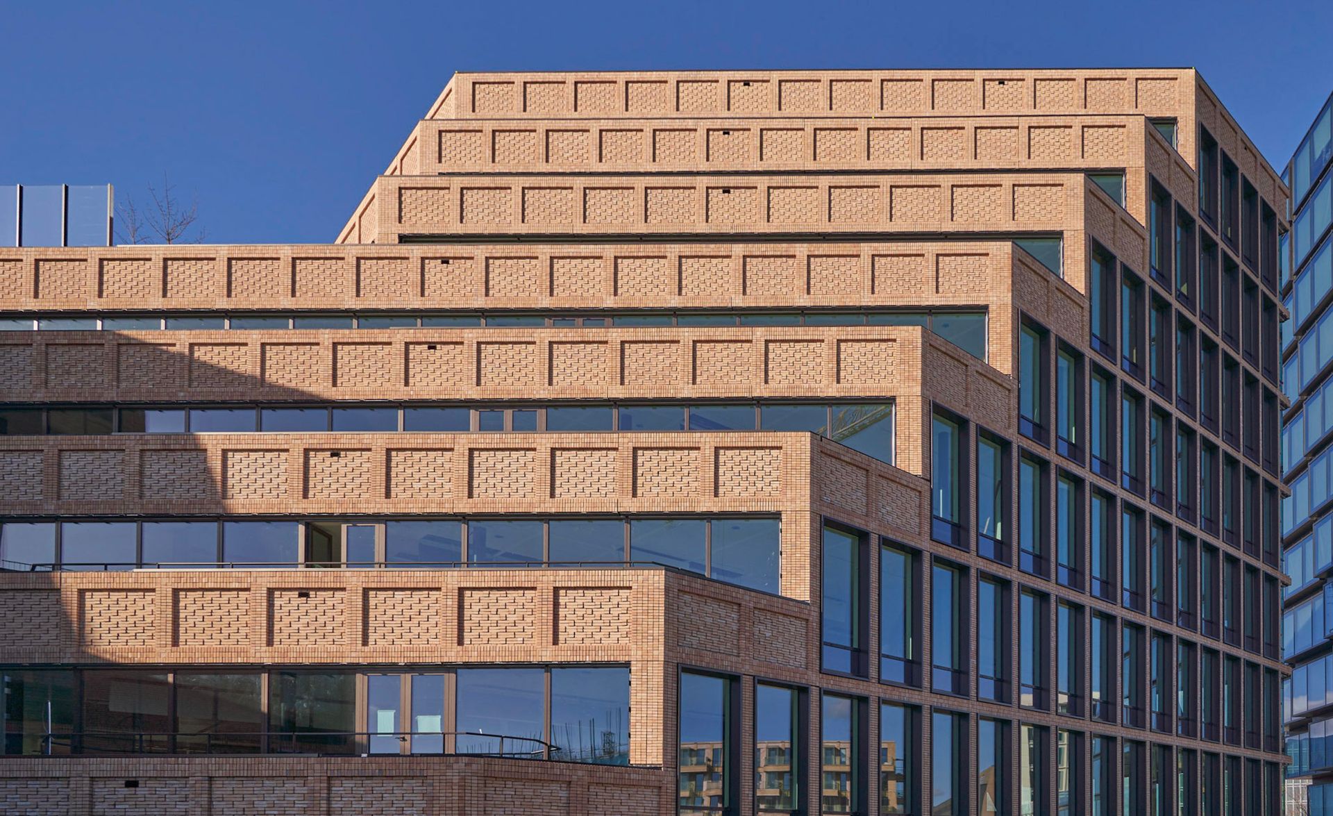 Een groot bakstenen gebouw met veel ramen en een blauwe lucht op de achtergrond.