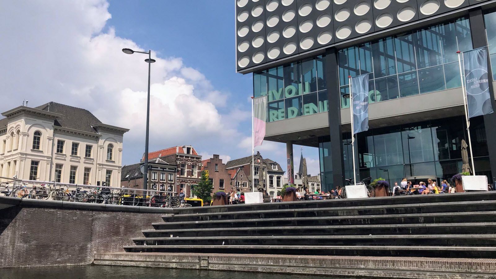 Een groot gebouw met veel ramen staat naast een rivier.