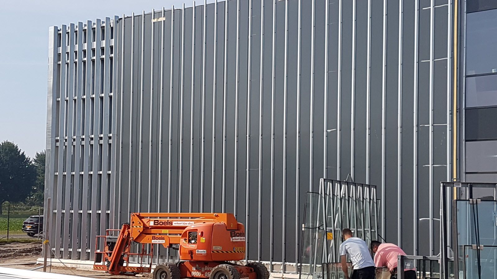 Er wordt een groot gebouw gebouwd met daarvoor een vorkheftruck.