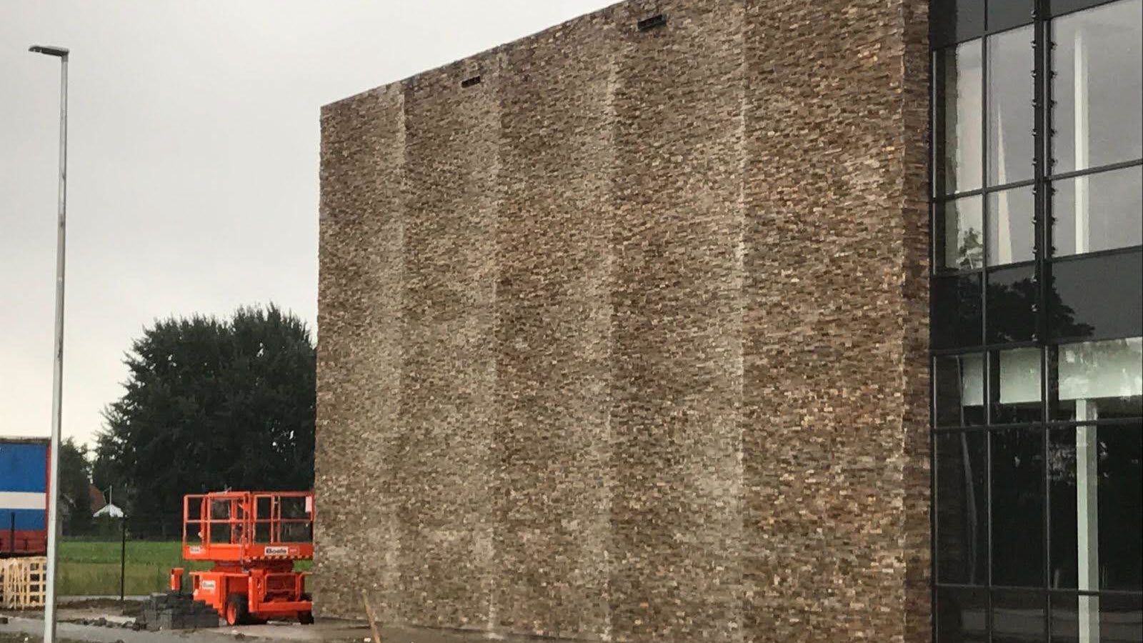 Er wordt een grote bakstenen muur aan de zijkant van een gebouw gebouwd.