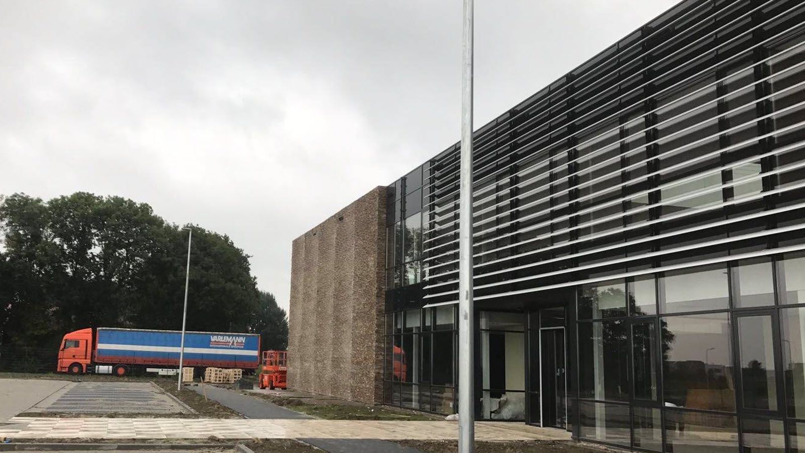 Een blauw-witte vrachtwagen staat geparkeerd voor een gebouw.