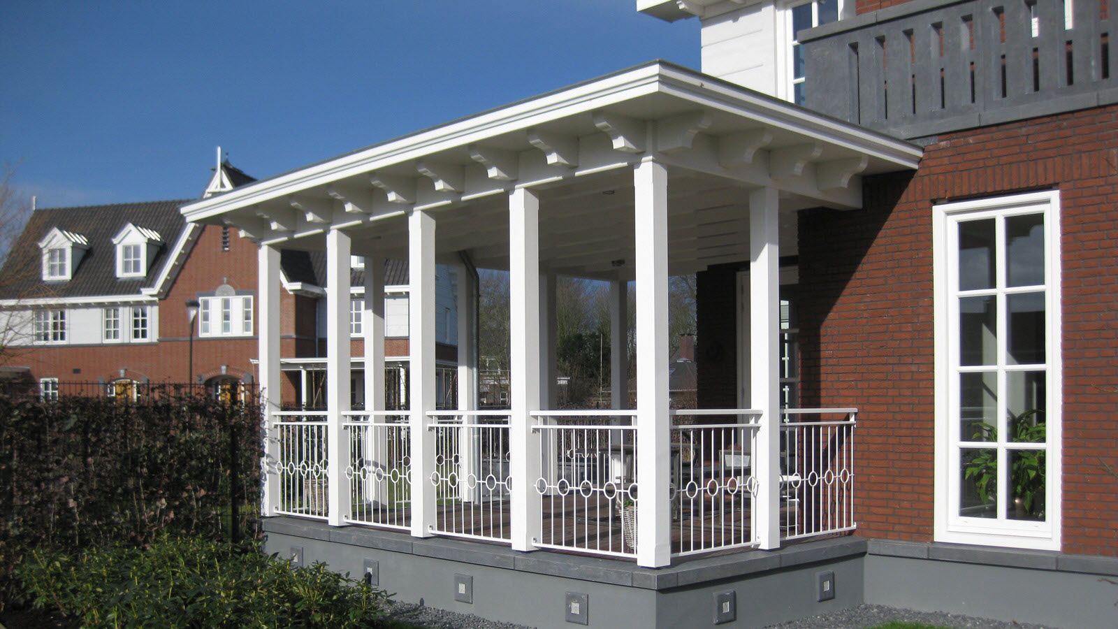 Een bakstenen huis met een veranda met witte zuilen