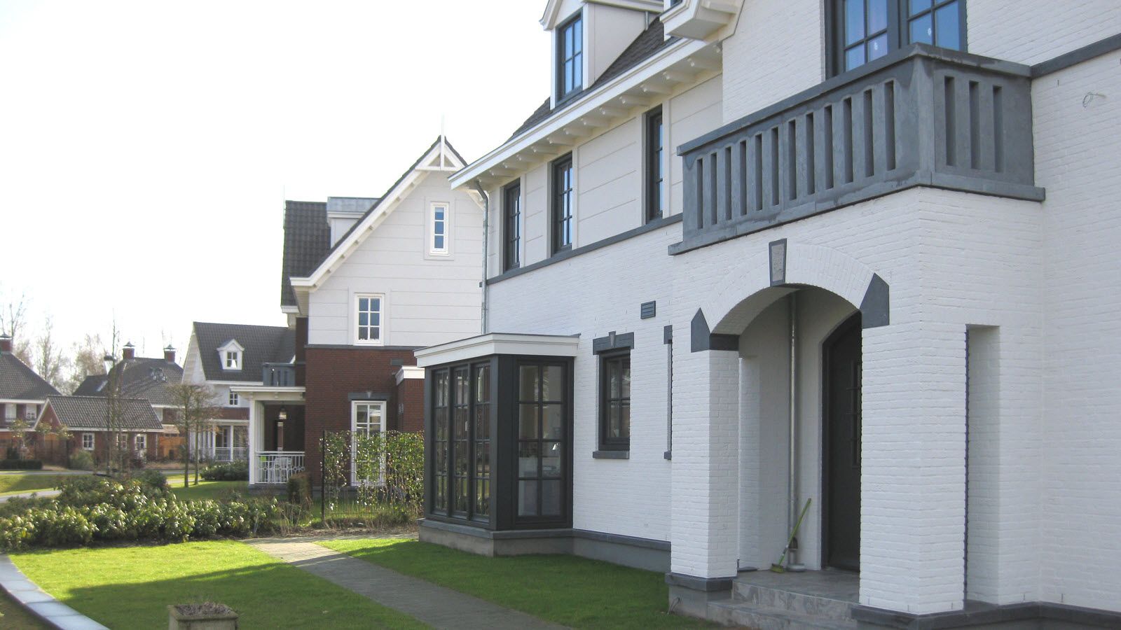 Een wit huis met een balkon en een gazon ervoor.