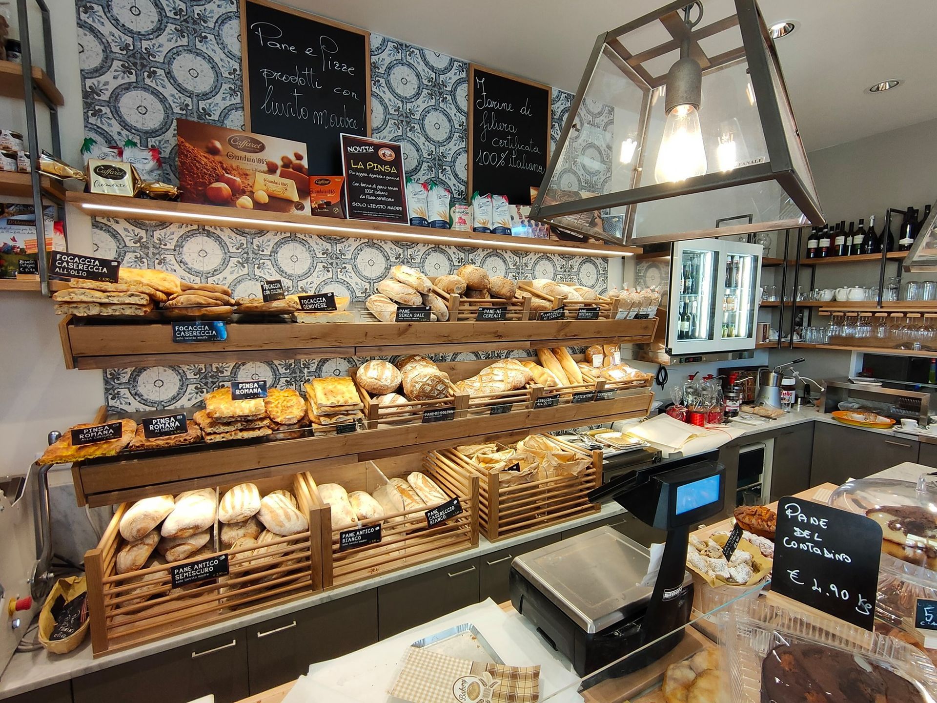 Il bancone di una panetteria espone vari tipi di pane, pasticcini e croissant su scaffali di legno