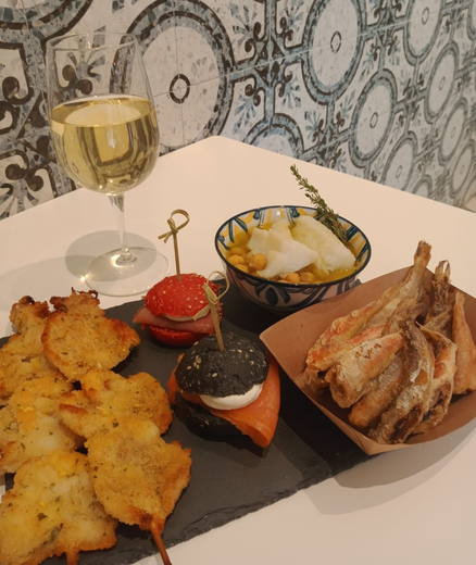 Un bicchiere di vino bianco servito con un piatto di tapas assortite