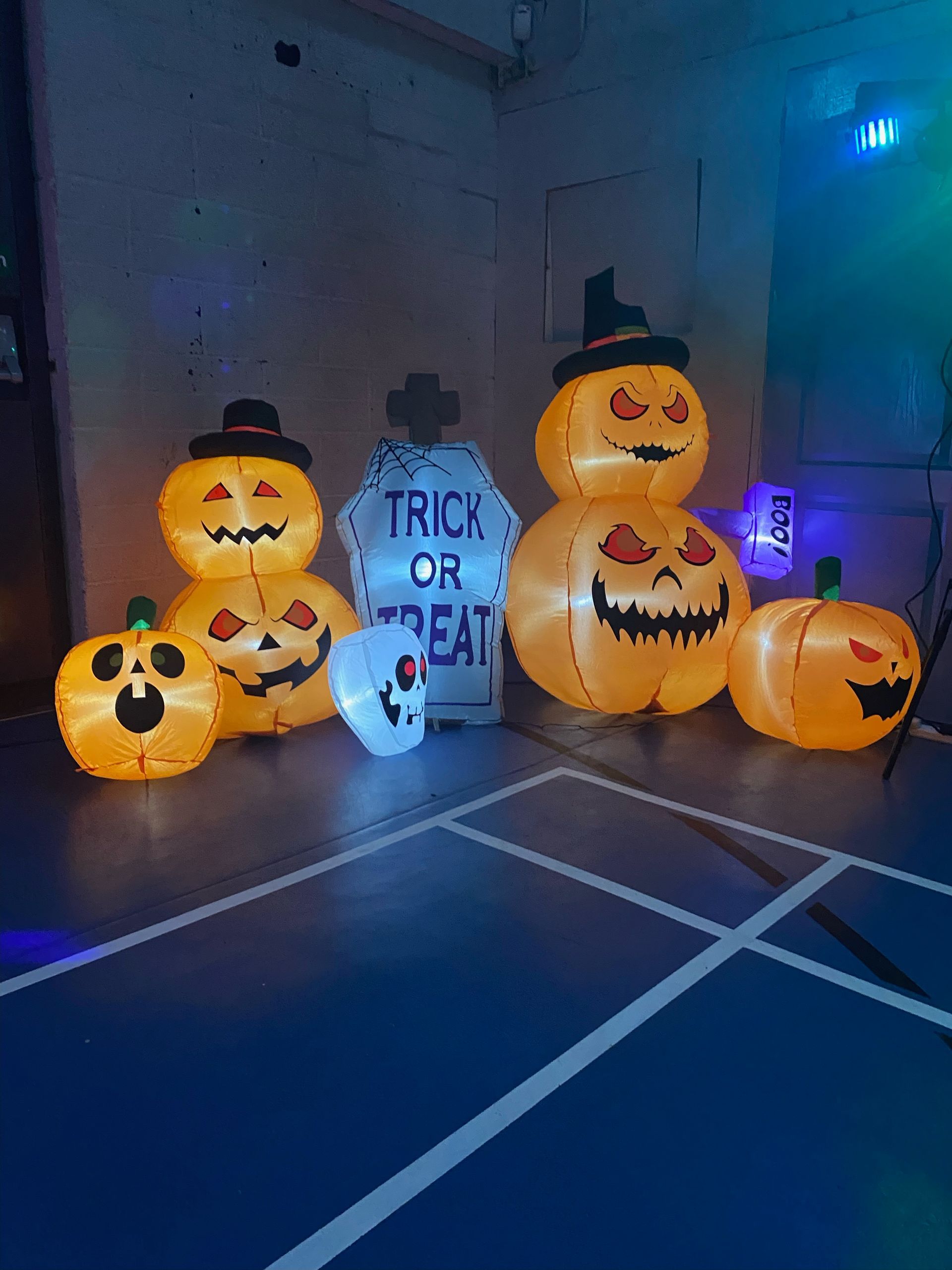 Halloween inflatable pumpkins and decorations in a room with blue lights, with a 
