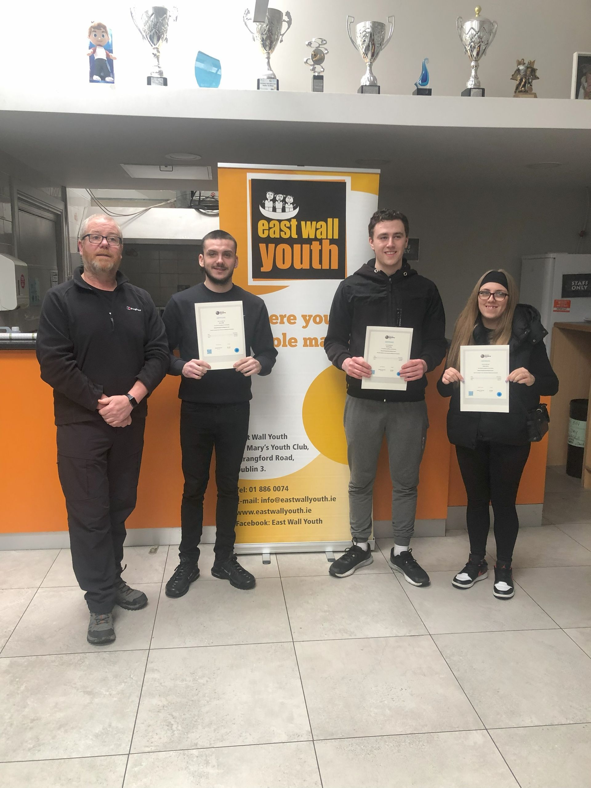 Four people holding certificates in front of a 