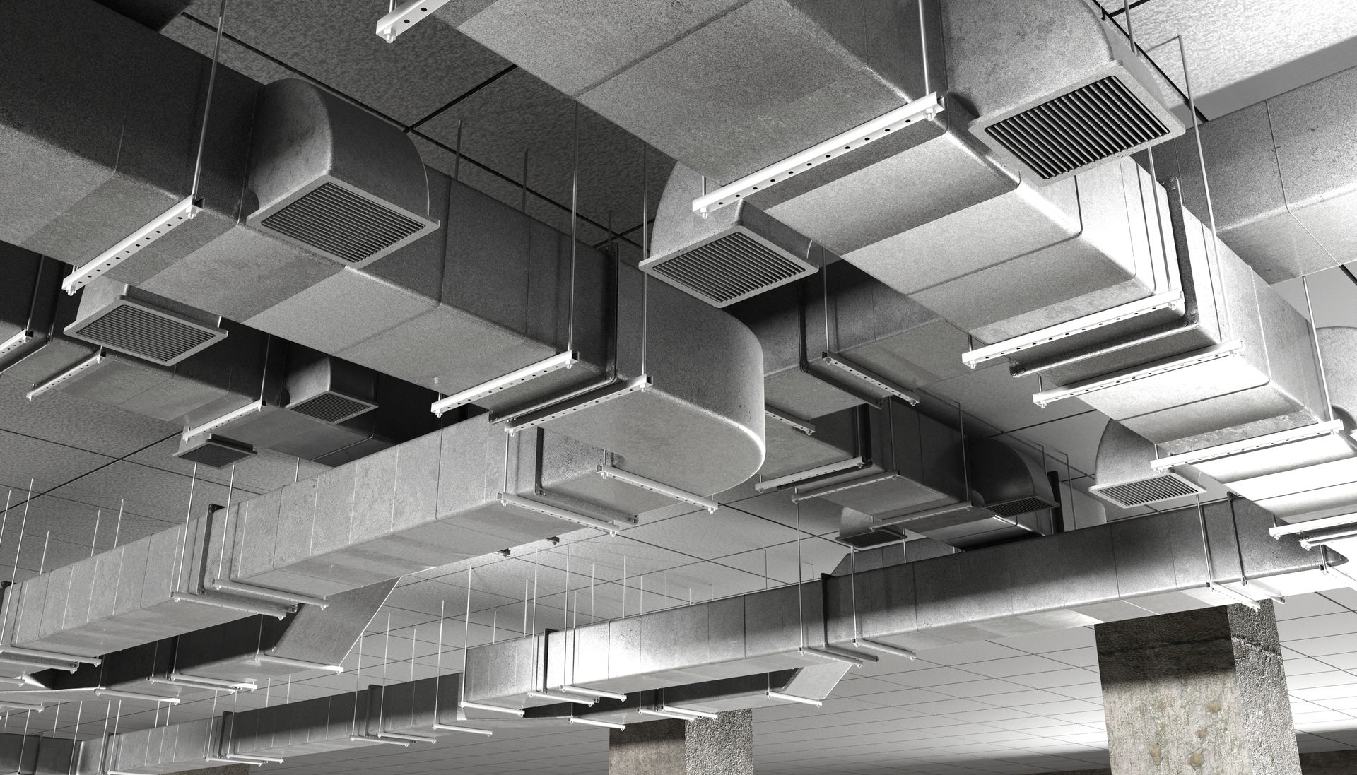 Gray ventilation ducts and ceiling vents in an industrial setting.