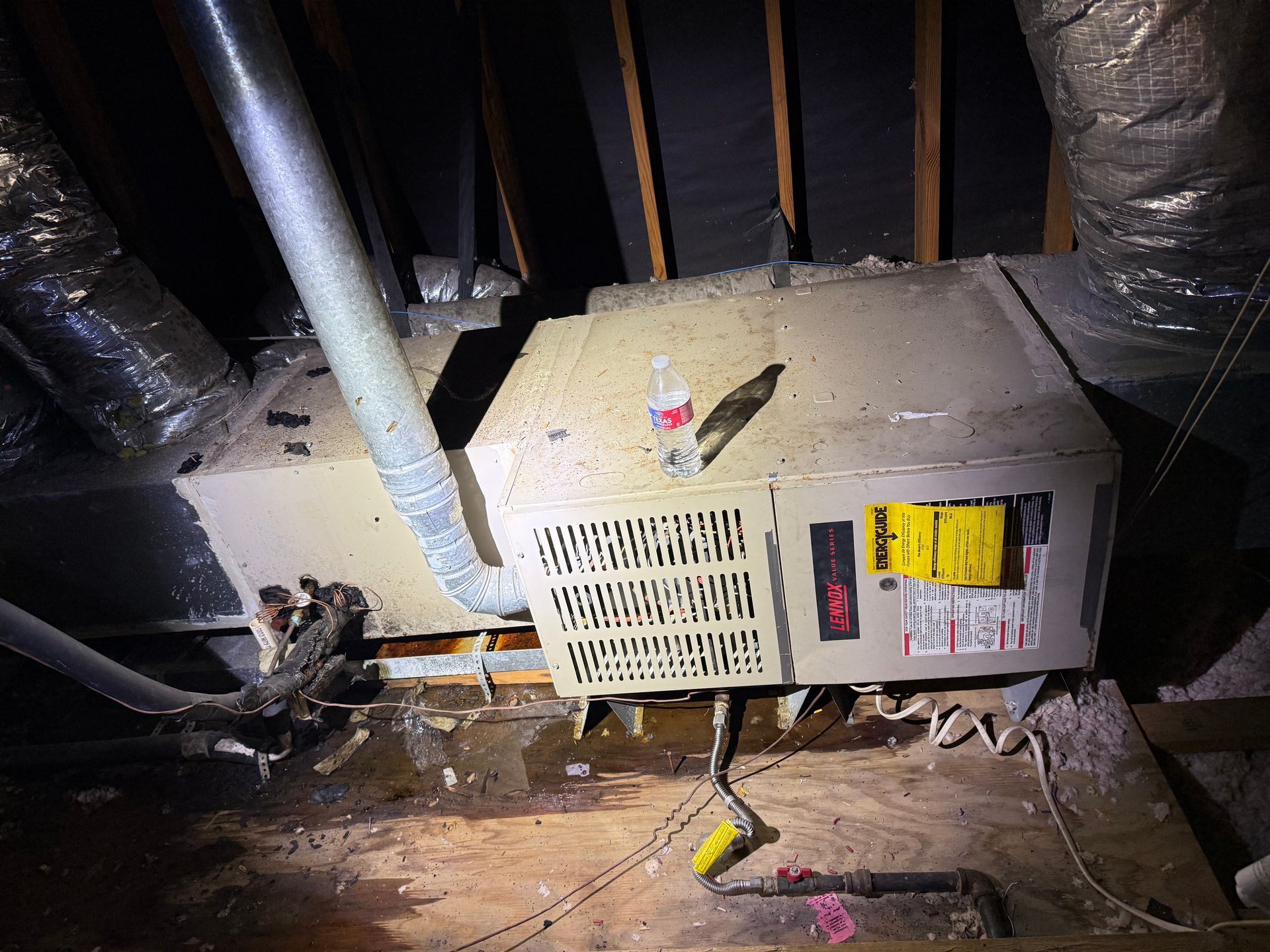 HVAC technician in yellow vest and hard hat repairs an air conditioning unit on a rooftop.