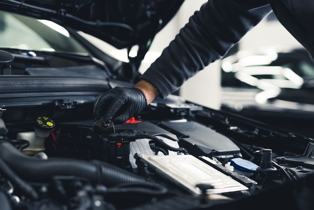 A man is working on the engine of a car with the hood open.