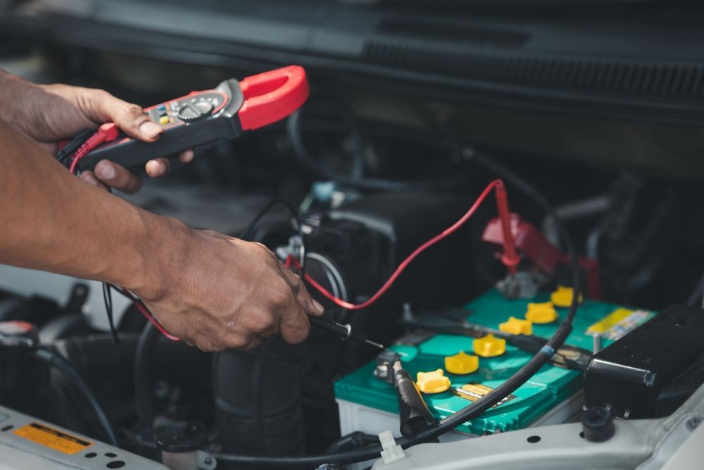 A man is working on a car battery with a clamp.