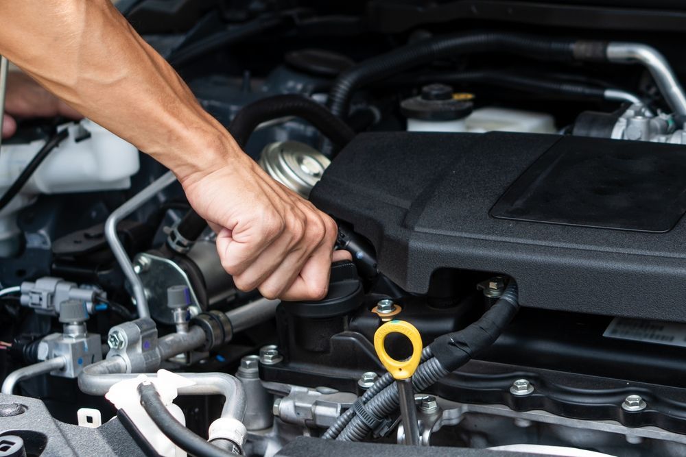 A man is working on the engine of a car with a wrench.